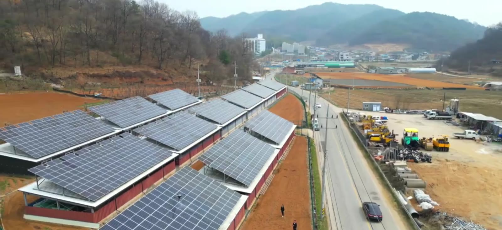산자락 도로변에 위치한 축사 2개 동의 지붕형 태양광 발전소 전경